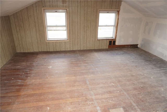 additional living space featuring lofted ceiling, wood walls, and wood-type flooring