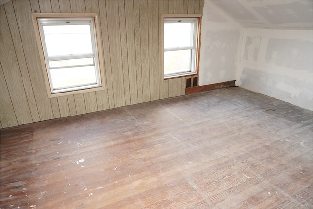 additional living space with hardwood / wood-style floors and wood walls