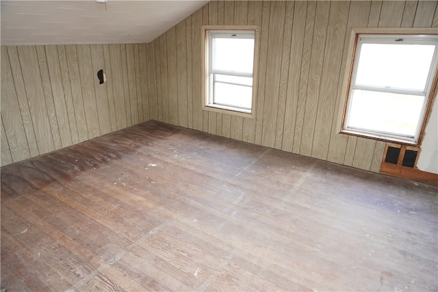 additional living space with light wood-type flooring, wooden walls, and vaulted ceiling