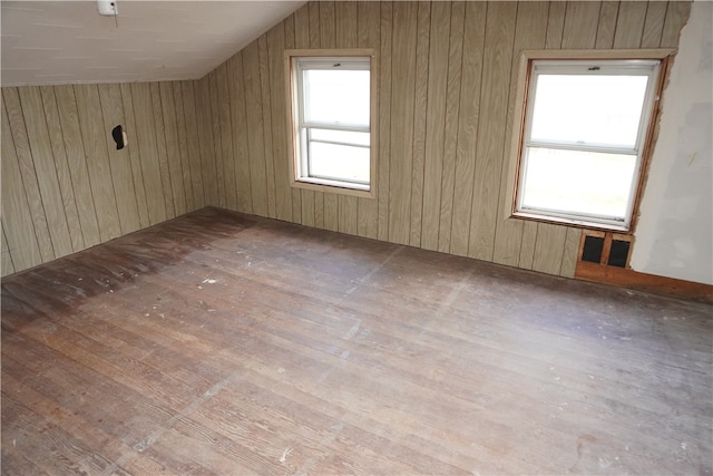 bonus room with wood-type flooring, wooden walls, and vaulted ceiling