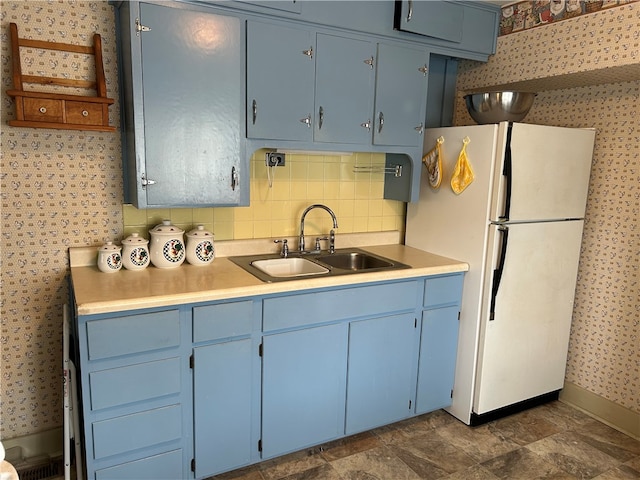 kitchen with white fridge, blue cabinets, and sink