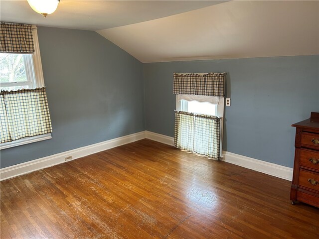 unfurnished bedroom with multiple windows, wood-type flooring, and vaulted ceiling