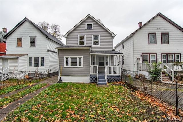 rear view of property featuring a lawn and a porch