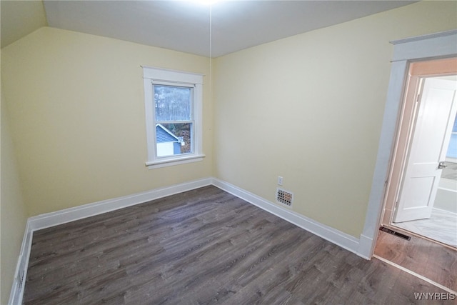 empty room featuring dark wood-type flooring and lofted ceiling