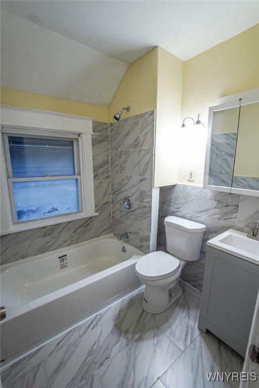 full bathroom with vanity, tiled shower / bath, vaulted ceiling, toilet, and tile walls