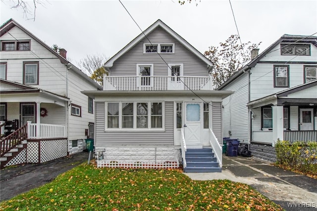 bungalow-style house featuring a balcony and a front lawn