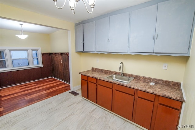 kitchen with a notable chandelier, sink, decorative light fixtures, and light wood-type flooring