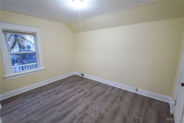 unfurnished room with vaulted ceiling and dark wood-type flooring