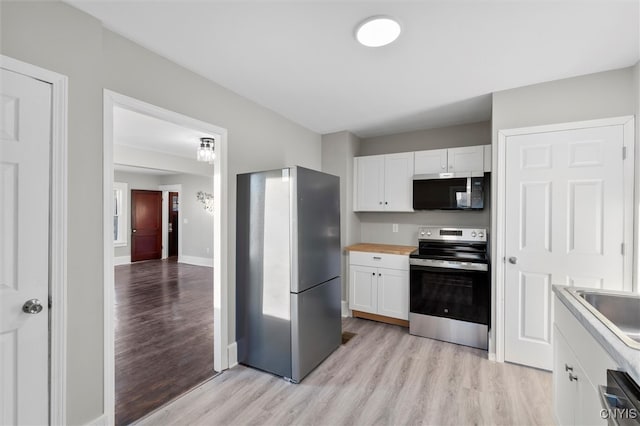 kitchen with light wood-type flooring, stainless steel appliances, white cabinetry, and sink