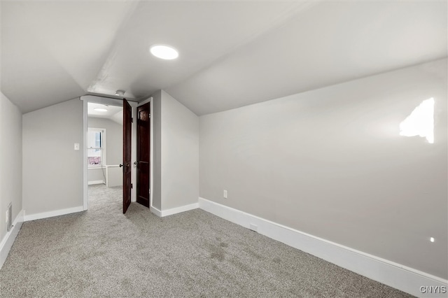 additional living space featuring light colored carpet and vaulted ceiling