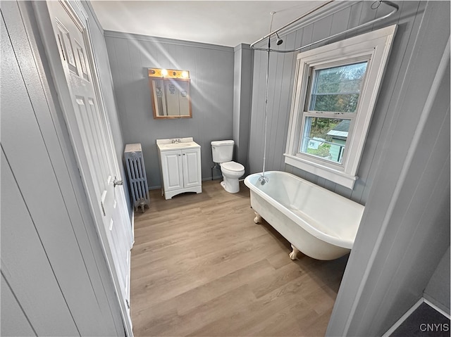 bathroom with vanity, a bath, hardwood / wood-style flooring, radiator heating unit, and toilet