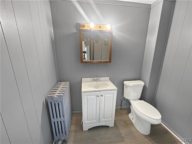 bathroom featuring hardwood / wood-style floors, wood walls, and radiator