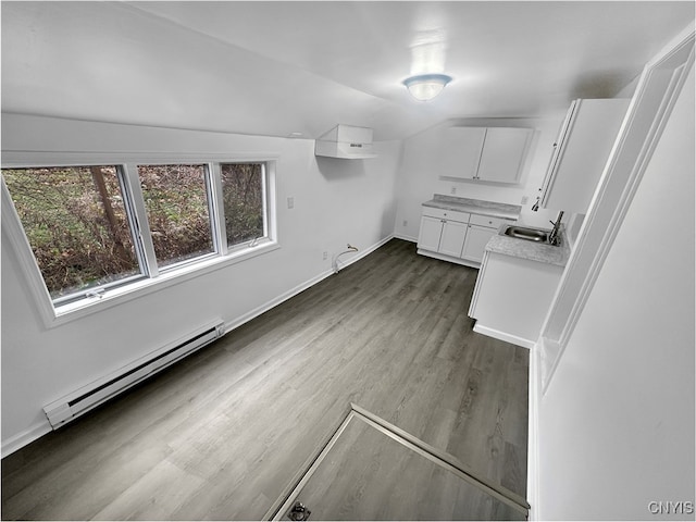 bathroom featuring hardwood / wood-style flooring, lofted ceiling, sink, and a baseboard heating unit