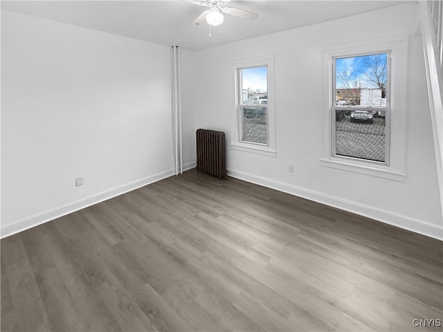 spare room with radiator heating unit, ceiling fan, and dark wood-type flooring