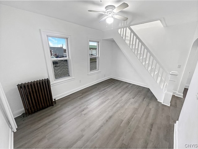 unfurnished living room with hardwood / wood-style floors, ceiling fan, and radiator heating unit