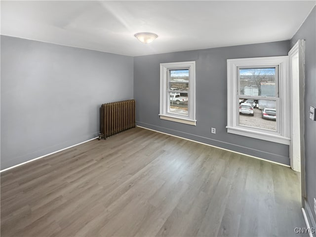 empty room featuring radiator heating unit and light wood-type flooring