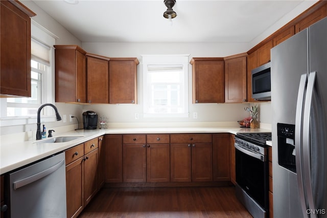 kitchen with appliances with stainless steel finishes, dark hardwood / wood-style flooring, and sink