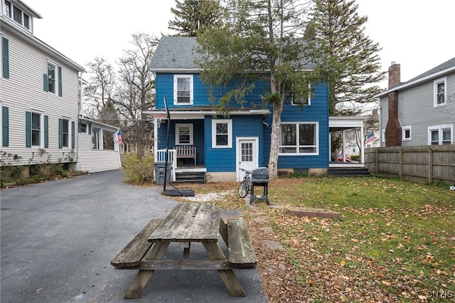 rear view of house with covered porch and a yard