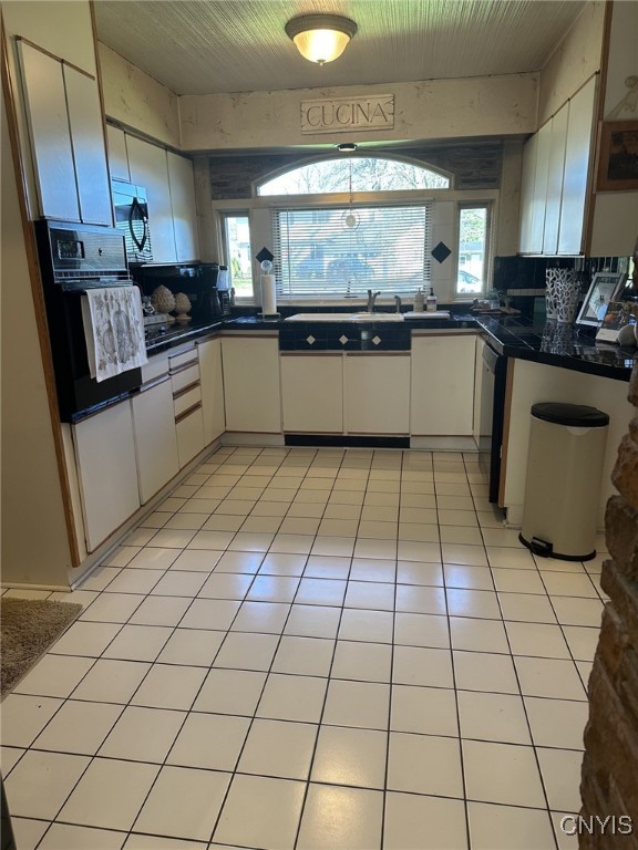 kitchen featuring sink, light tile patterned floors, tasteful backsplash, white cabinets, and black appliances