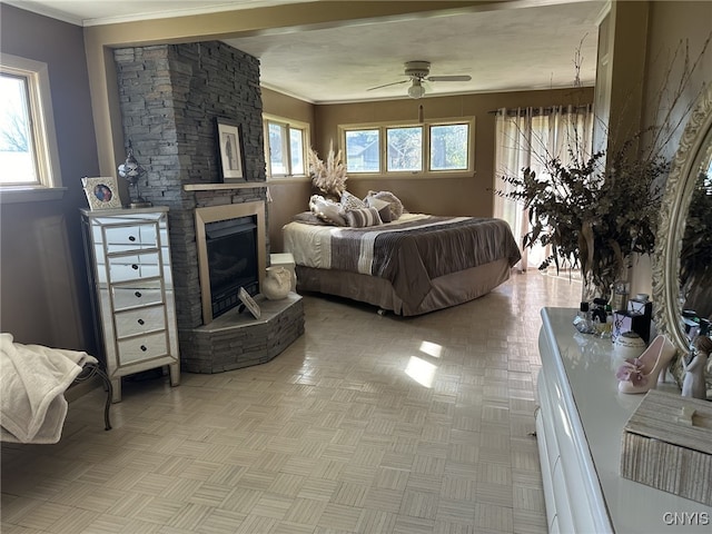 bedroom featuring ceiling fan, a stone fireplace, and crown molding