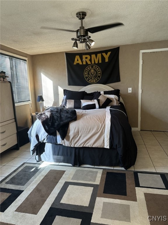 bedroom with ceiling fan, light tile patterned floors, and a textured ceiling