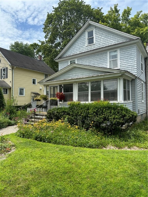 view of front facade with a sunroom and a front yard