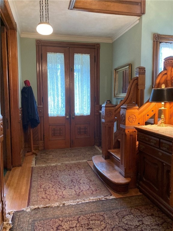 foyer entrance with light wood-type flooring, ornamental molding, and french doors