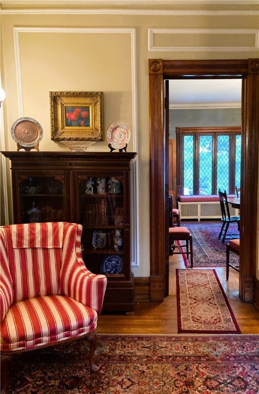 living area with wood-type flooring and crown molding