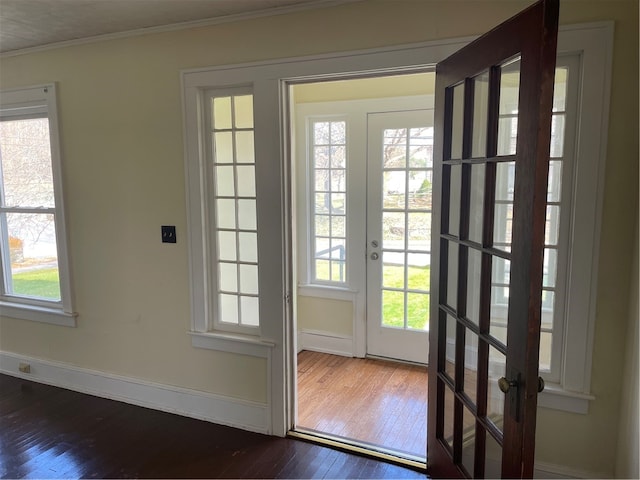 doorway with dark hardwood / wood-style flooring, ornamental molding, and a healthy amount of sunlight