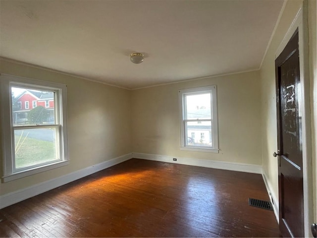 empty room with crown molding, dark hardwood / wood-style floors, and a wealth of natural light