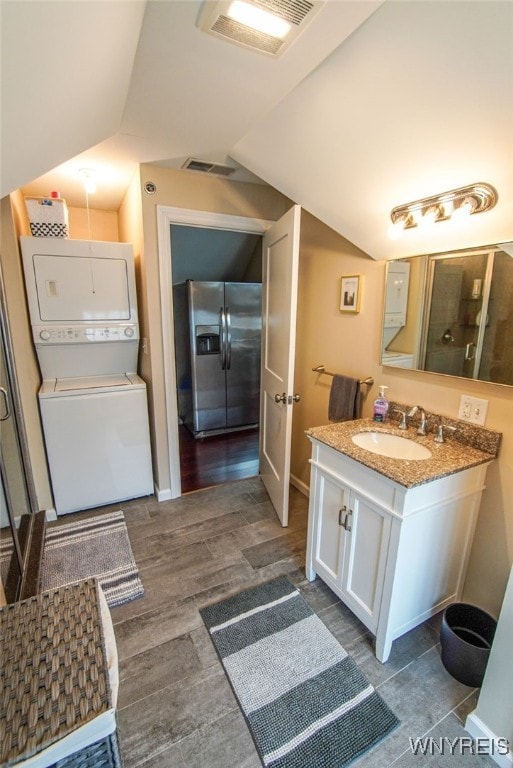 67 Harvard Pl, Buffalo, NY 14209 - bathroom featuring vanity, wood-type flooring, lofted ceiling, and stacked washer and clothes dryer