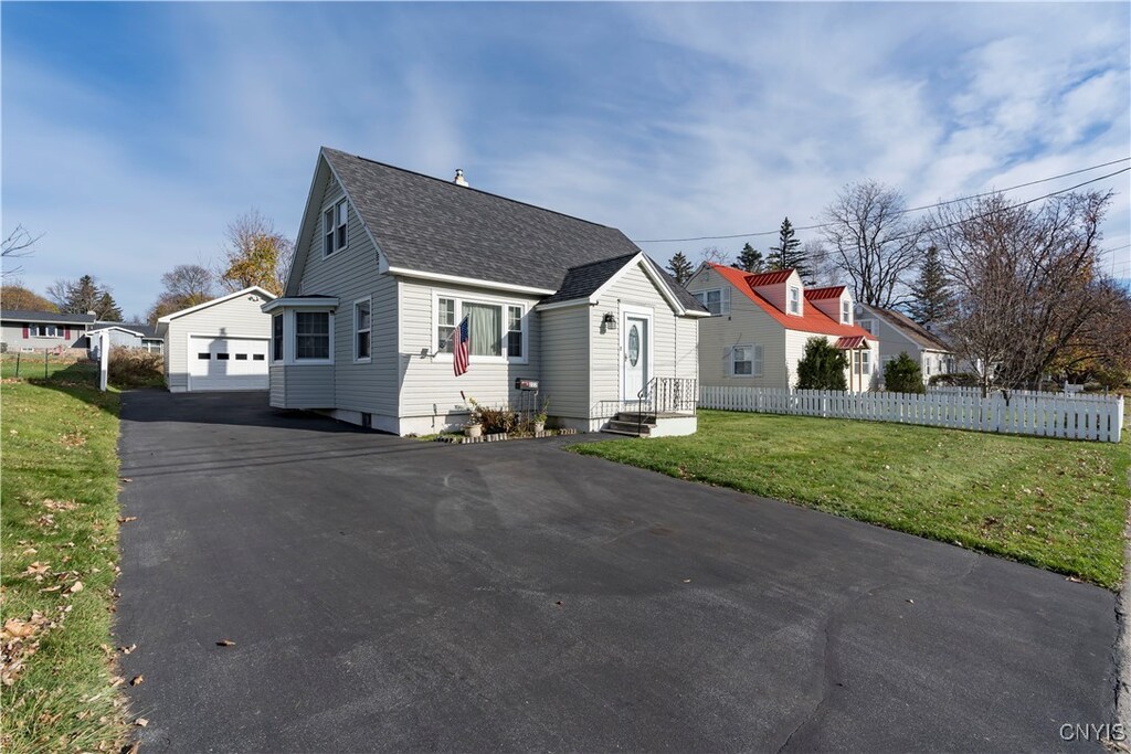 view of front facade with an outbuilding, a garage, and a front lawn