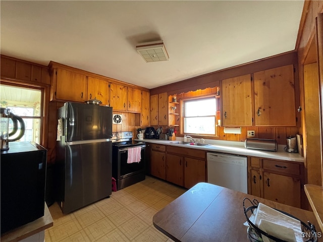 kitchen featuring wooden walls, sink, and appliances with stainless steel finishes