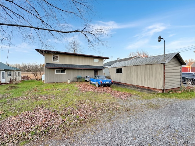 rear view of house featuring an outbuilding and a lawn