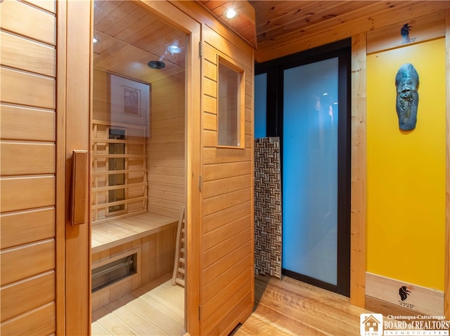 view of sauna featuring hardwood / wood-style flooring, wooden ceiling, and wooden walls