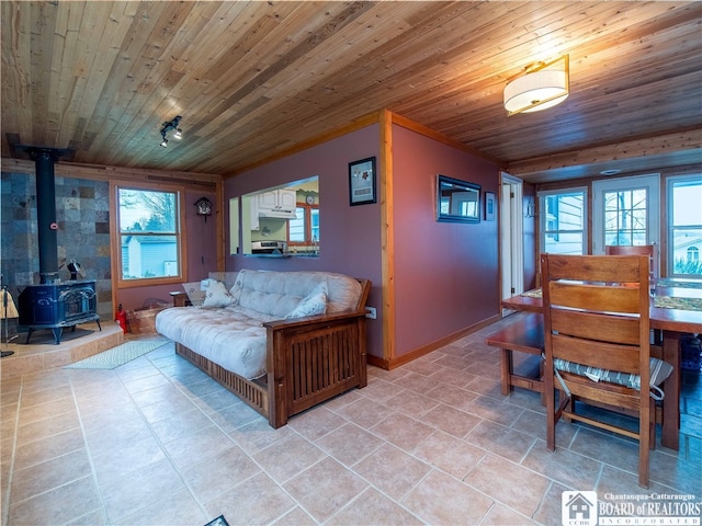 living room featuring a wood stove, light tile patterned flooring, and wood ceiling