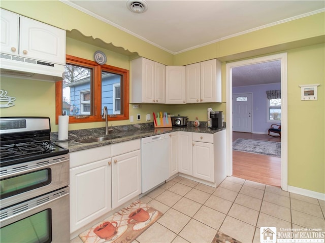 kitchen featuring white dishwasher, white cabinets, sink, stainless steel gas stove, and plenty of natural light