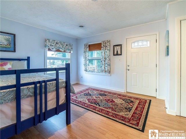 entrance foyer featuring hardwood / wood-style floors, a textured ceiling, and crown molding