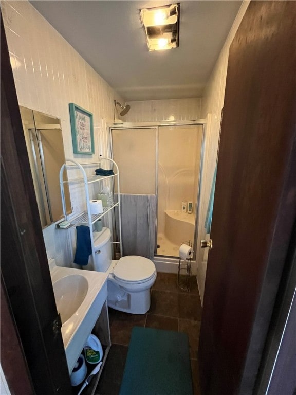 bathroom featuring tile patterned floors, toilet, and a shower with door