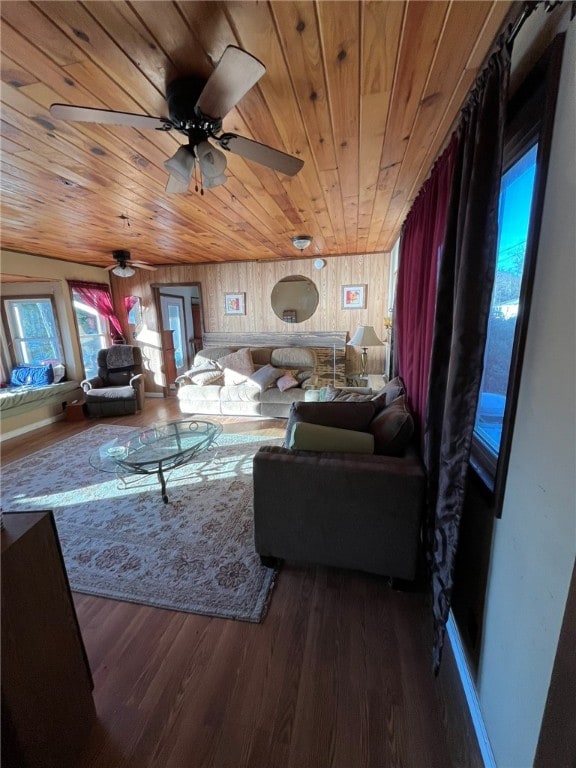 living room with wooden walls, dark wood-type flooring, ceiling fan, and wood ceiling