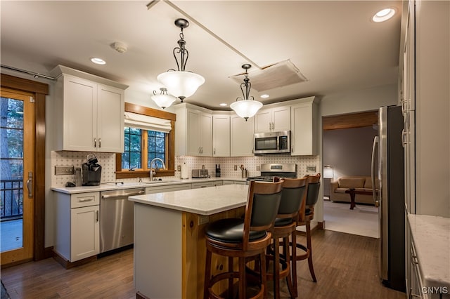 kitchen featuring appliances with stainless steel finishes, sink, white cabinets, a center island, and dark hardwood / wood-style floors