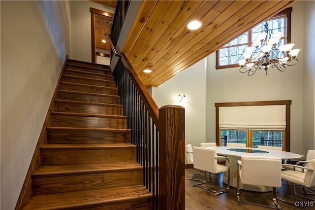 staircase with a chandelier, wood-type flooring, vaulted ceiling, and wooden ceiling