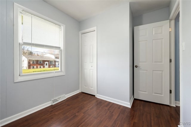 unfurnished bedroom with dark wood-type flooring and a closet