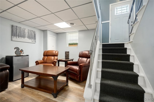 living room with light hardwood / wood-style flooring and a drop ceiling