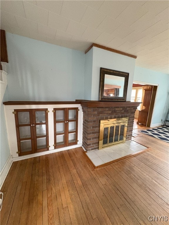 unfurnished living room with light hardwood / wood-style floors and a brick fireplace