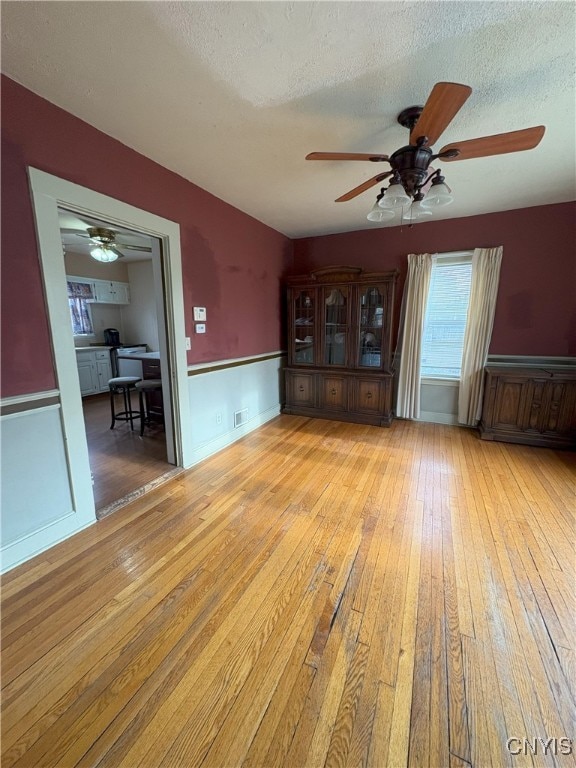 interior space featuring ceiling fan, a textured ceiling, and light hardwood / wood-style flooring