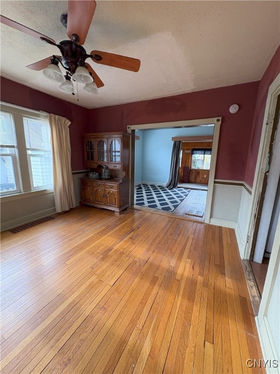 unfurnished living room featuring light hardwood / wood-style floors, a textured ceiling, and a wealth of natural light