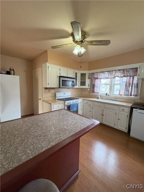 kitchen with white appliances, ceiling fan, decorative backsplash, light hardwood / wood-style floors, and white cabinetry