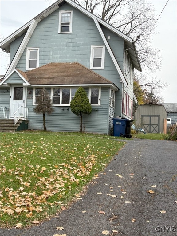 back of house with a shed and a lawn