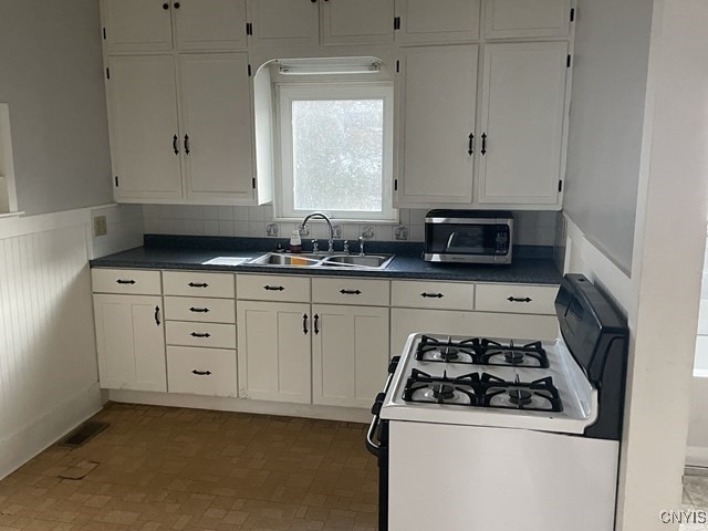20 Pearl St, Bainbridge, NY 13733 - kitchen with white gas range, a sink, stainless steel microwave, dark countertops, and white cabinetry